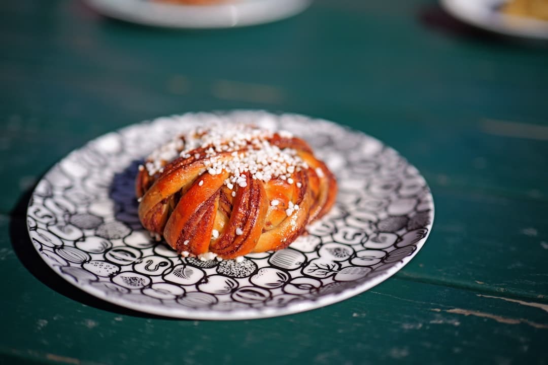 En enskild kanelbulle med pärlsocker på en mönstrad tallrik